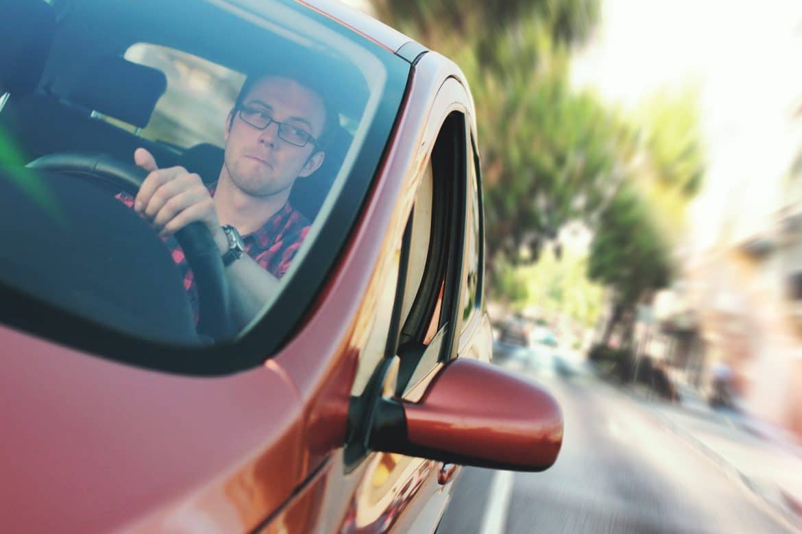 Un homme au volant d'une voiture rouge